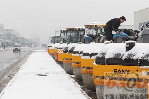 寒风中，工人细心地除去压路机上的积雪